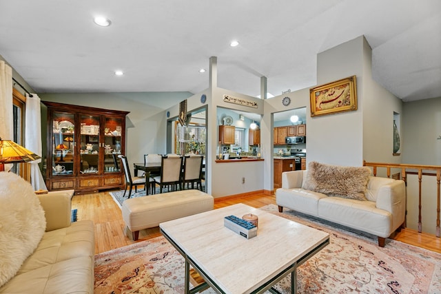 living area featuring vaulted ceiling, light wood finished floors, and recessed lighting