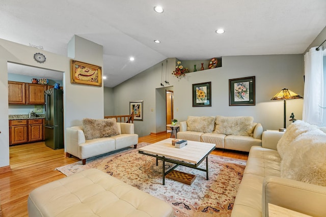 living area featuring vaulted ceiling, light wood-type flooring, and recessed lighting