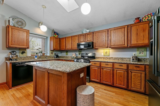 kitchen with stainless steel range with gas stovetop, black dishwasher, a skylight, brown cabinetry, and light wood finished floors