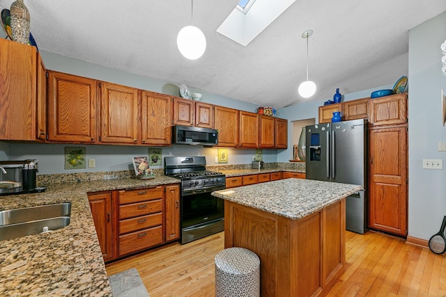 kitchen with range with gas stovetop, stainless steel fridge with ice dispenser, light wood-style flooring, a skylight, and vaulted ceiling