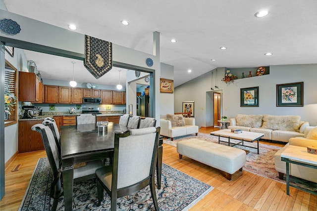 dining area with lofted ceiling, light wood-type flooring, recessed lighting, and baseboards