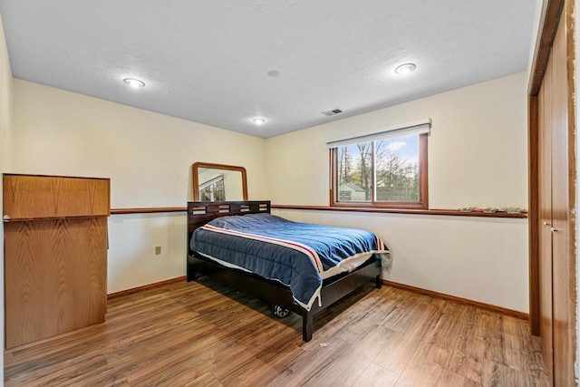 bedroom with baseboards, wood finished floors, a textured ceiling, and recessed lighting