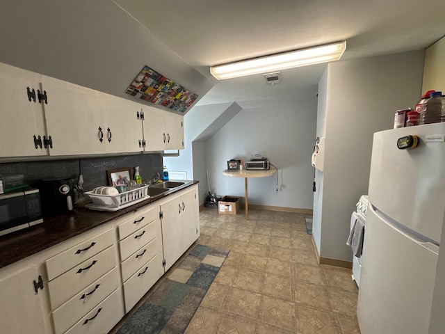 2526 Garnet Ave, Slayton, MN 56172 - kitchen with freestanding refrigerator, visible vents, black microwave, white cabinets, and dark countertops