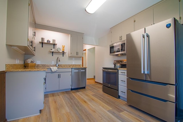 kitchen with stainless steel appliances, light wood-style floors, a sink, and open shelves