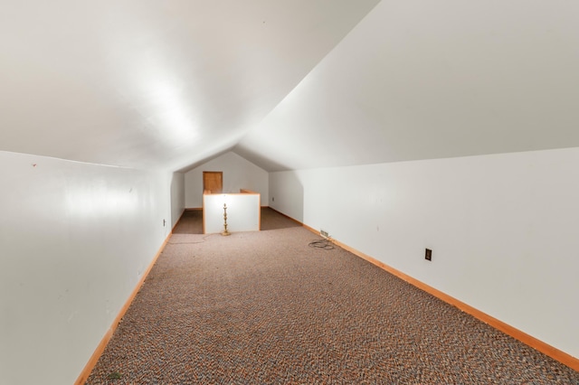 additional living space featuring baseboards, lofted ceiling, and light carpet