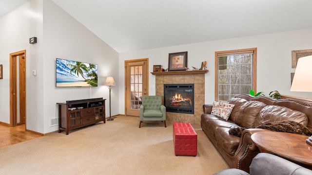 living room with light colored carpet, a tile fireplace, baseboards, and high vaulted ceiling