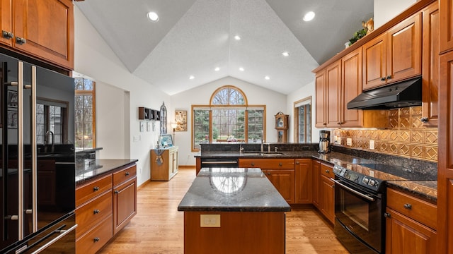 kitchen featuring black appliances, under cabinet range hood, vaulted ceiling, a peninsula, and a kitchen island