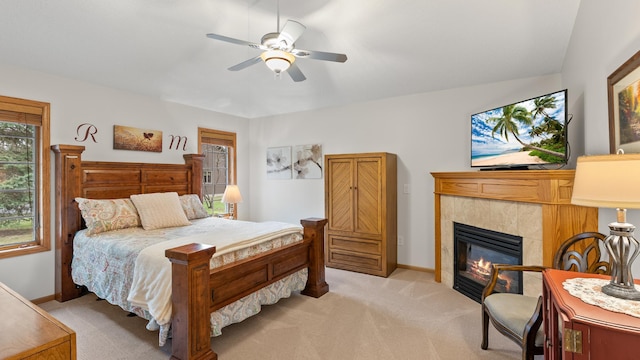 bedroom featuring a tiled fireplace, light carpet, and baseboards