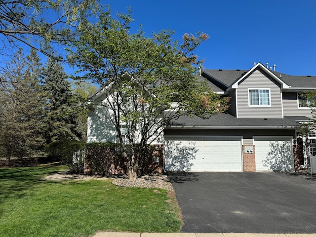 view of front of home featuring driveway, a garage, a front lawn, and a shingled roof