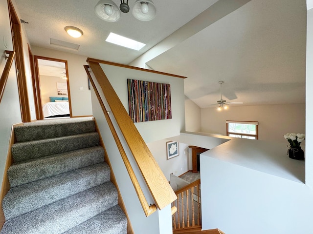 staircase with lofted ceiling and a ceiling fan