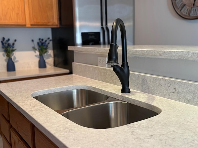 kitchen view of a sink, light countertops, and brown cabinetry