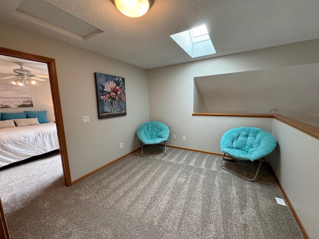 sitting room featuring carpet flooring, a skylight, baseboards, and a textured ceiling