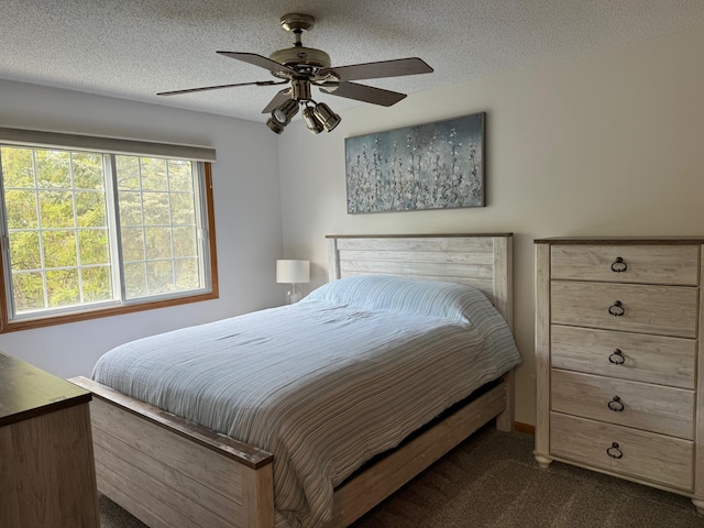 bedroom with dark colored carpet, a textured ceiling, and ceiling fan