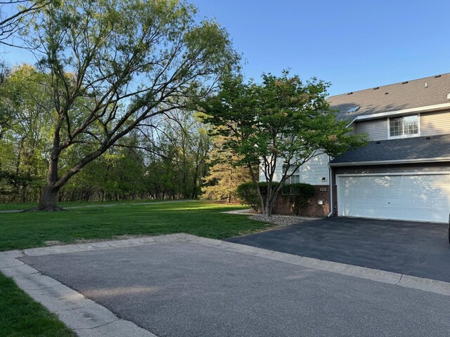 view of grassy yard featuring driveway and a garage