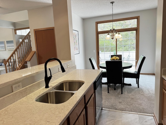 kitchen featuring a sink, dishwasher, hanging light fixtures, a chandelier, and light stone countertops