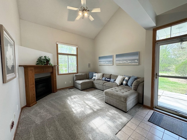 living area featuring healthy amount of natural light, a ceiling fan, baseboards, a fireplace, and high vaulted ceiling