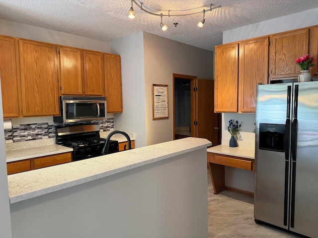 kitchen with appliances with stainless steel finishes, tasteful backsplash, brown cabinetry, and a textured ceiling