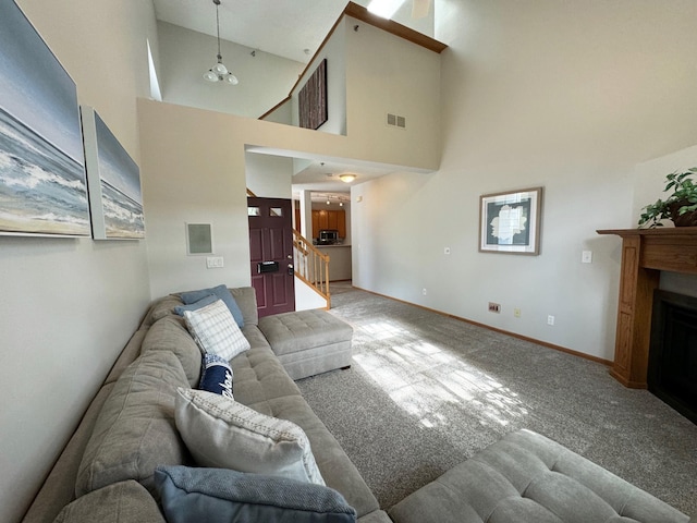 living area featuring carpet floors, a towering ceiling, stairway, a fireplace, and baseboards