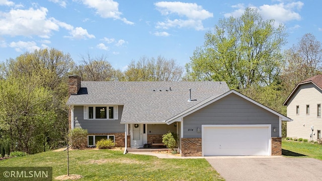 tri-level home featuring a chimney, a front lawn, asphalt driveway, a garage, and brick siding