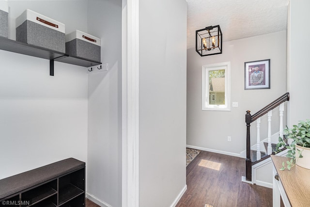 mudroom featuring dark wood-style flooring, baseboards, a chandelier, and a textured ceiling