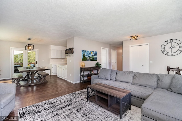 living area with dark wood finished floors, a textured ceiling, and baseboards