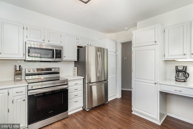 kitchen featuring stainless steel appliances, light countertops, white cabinetry, and dark wood-type flooring