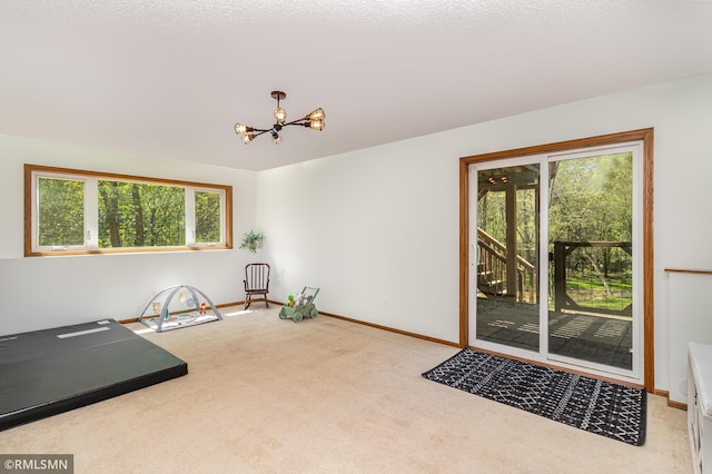 workout area featuring a chandelier, carpet, and baseboards