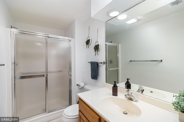 bathroom with toilet, a shower stall, and vanity