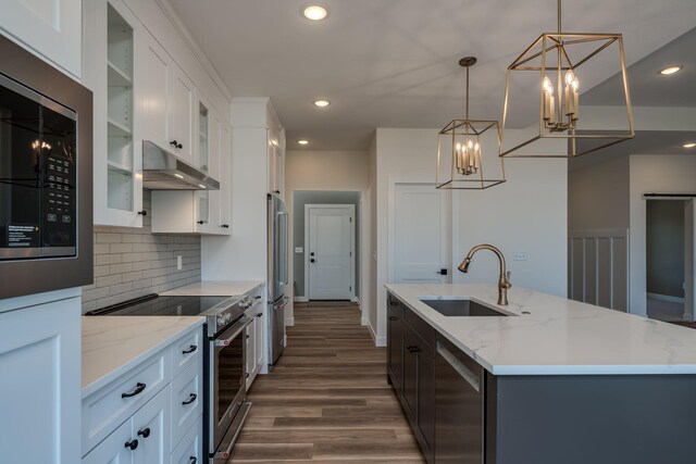 kitchen featuring a sink, under cabinet range hood, an inviting chandelier, backsplash, and high quality appliances