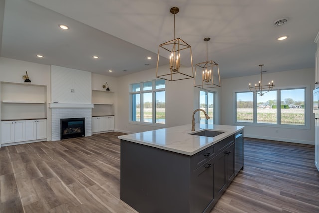 kitchen featuring stainless steel dishwasher, baseboards, an inviting chandelier, a sink, and dark wood-style floors
