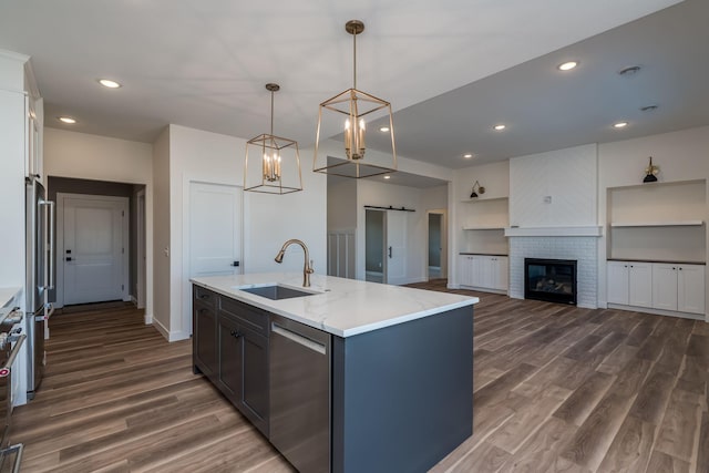 kitchen featuring a center island with sink, dark wood-type flooring, a barn door, and a sink