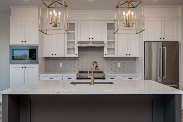 kitchen featuring under cabinet range hood, a chandelier, decorative backsplash, and built in microwave