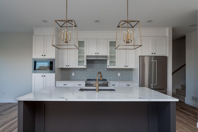 kitchen featuring high quality fridge, under cabinet range hood, baseboards, a sink, and crown molding