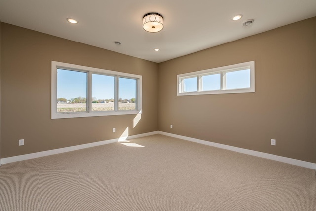 empty room featuring baseboards, light carpet, and recessed lighting