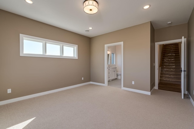 unfurnished bedroom with light colored carpet, recessed lighting, baseboards, and ensuite bath