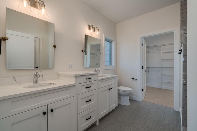 full bathroom with double vanity, a spacious closet, and toilet