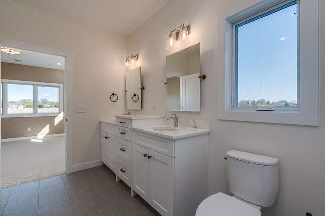 bathroom featuring toilet, baseboards, and vanity