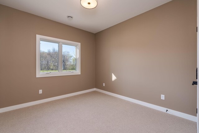 unfurnished room with light carpet and baseboards