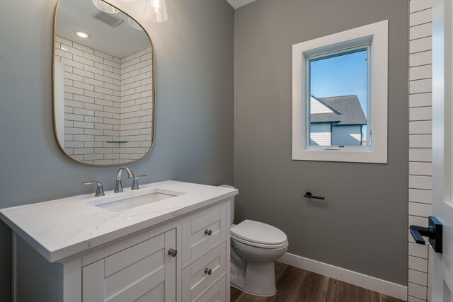 bathroom with wood finished floors, baseboards, toilet, and vanity