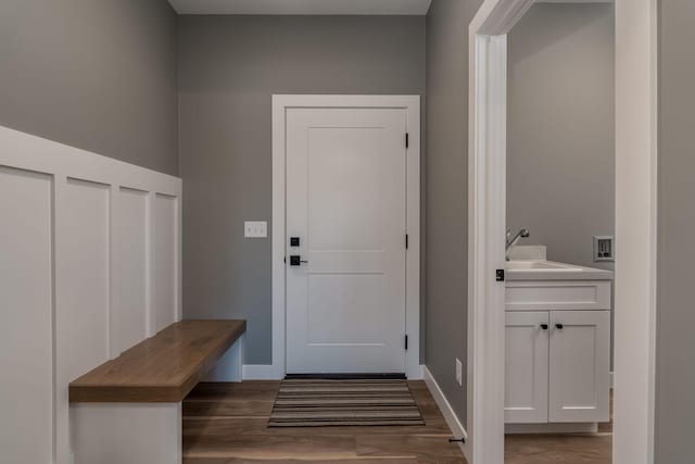 mudroom featuring a sink, wood finished floors, and baseboards
