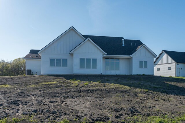 back of house featuring board and batten siding and roof with shingles