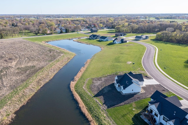 drone / aerial view of a nearby body of water and a tree filled landscape