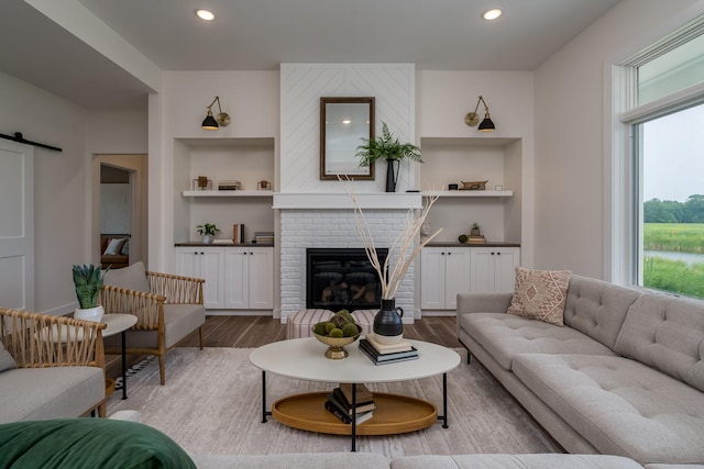 2132 Deerwood Dr, North Mankato, MN 56003 - living area with wood finished floors, built in shelves, a fireplace, recessed lighting, and a barn door