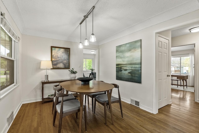 dining area with a textured ceiling, wood finished floors, healthy amount of natural light, and baseboards