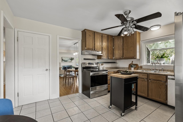 kitchen with stainless steel appliances, under cabinet range hood, a sink, light tile patterned floors, and ceiling fan