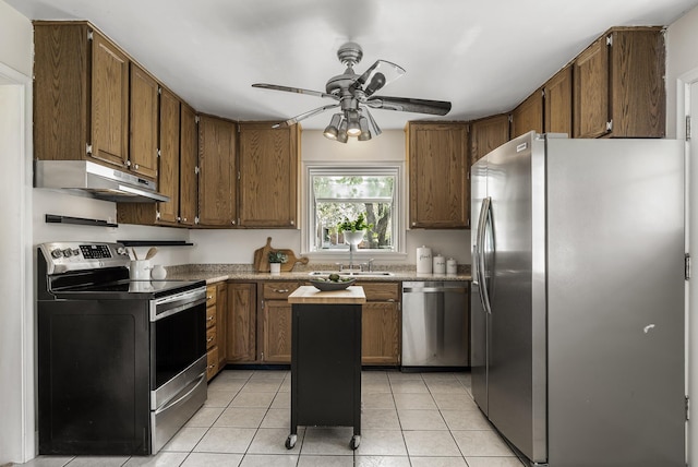kitchen with stainless steel appliances, under cabinet range hood, a sink, ceiling fan, and light tile patterned floors