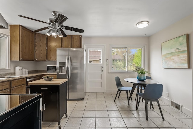 kitchen with appliances with stainless steel finishes, a ceiling fan, light tile patterned floors, and baseboards
