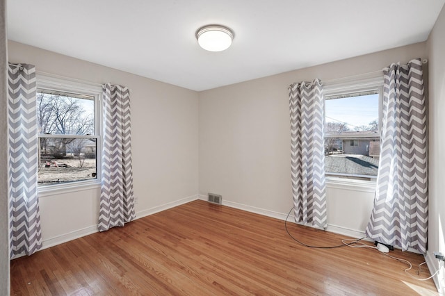 unfurnished room featuring wood finished floors, healthy amount of natural light, and baseboards