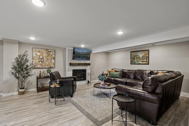 living room with baseboards, light wood finished floors, a fireplace, and recessed lighting