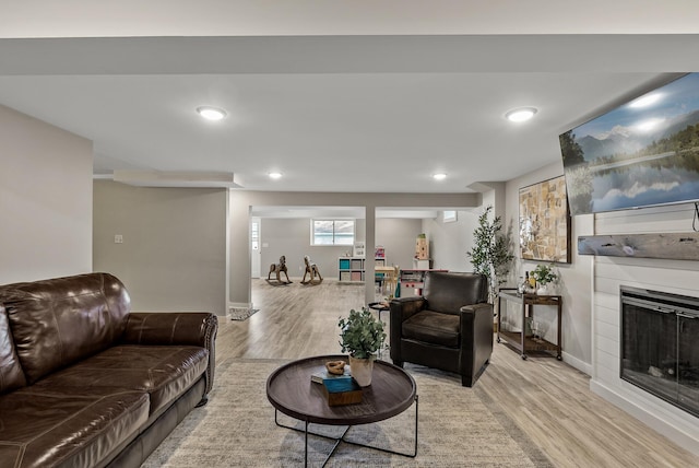 living room featuring wood finished floors, baseboards, a glass covered fireplace, and recessed lighting